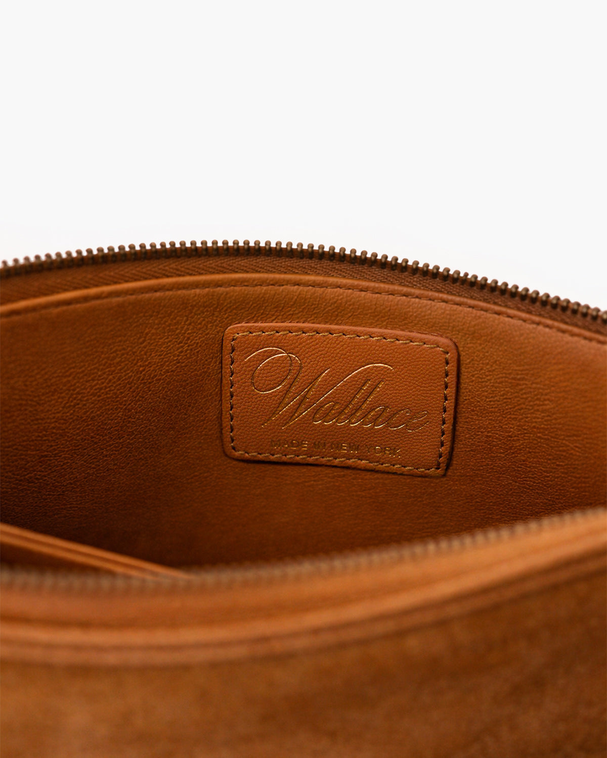 Close-up of a brown leather pouch with a visible brand label on a white background