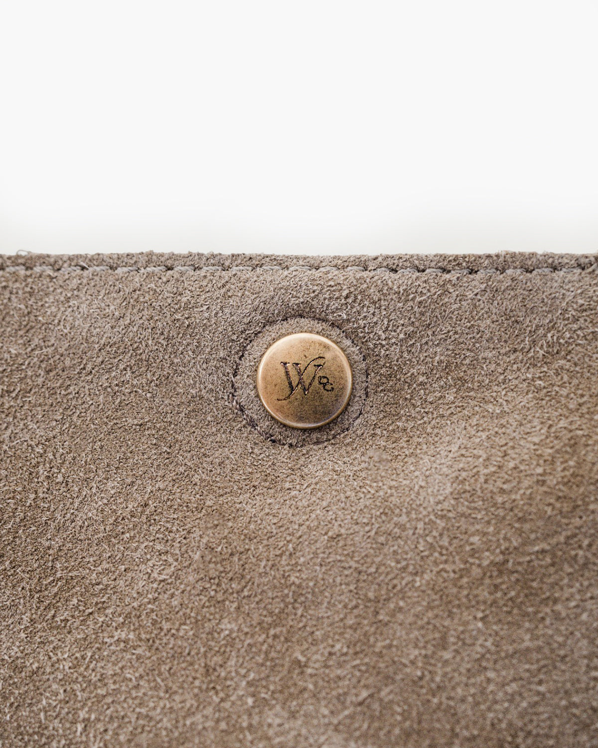 Close-up of a textured beige surface with a circular button featuring a logo.