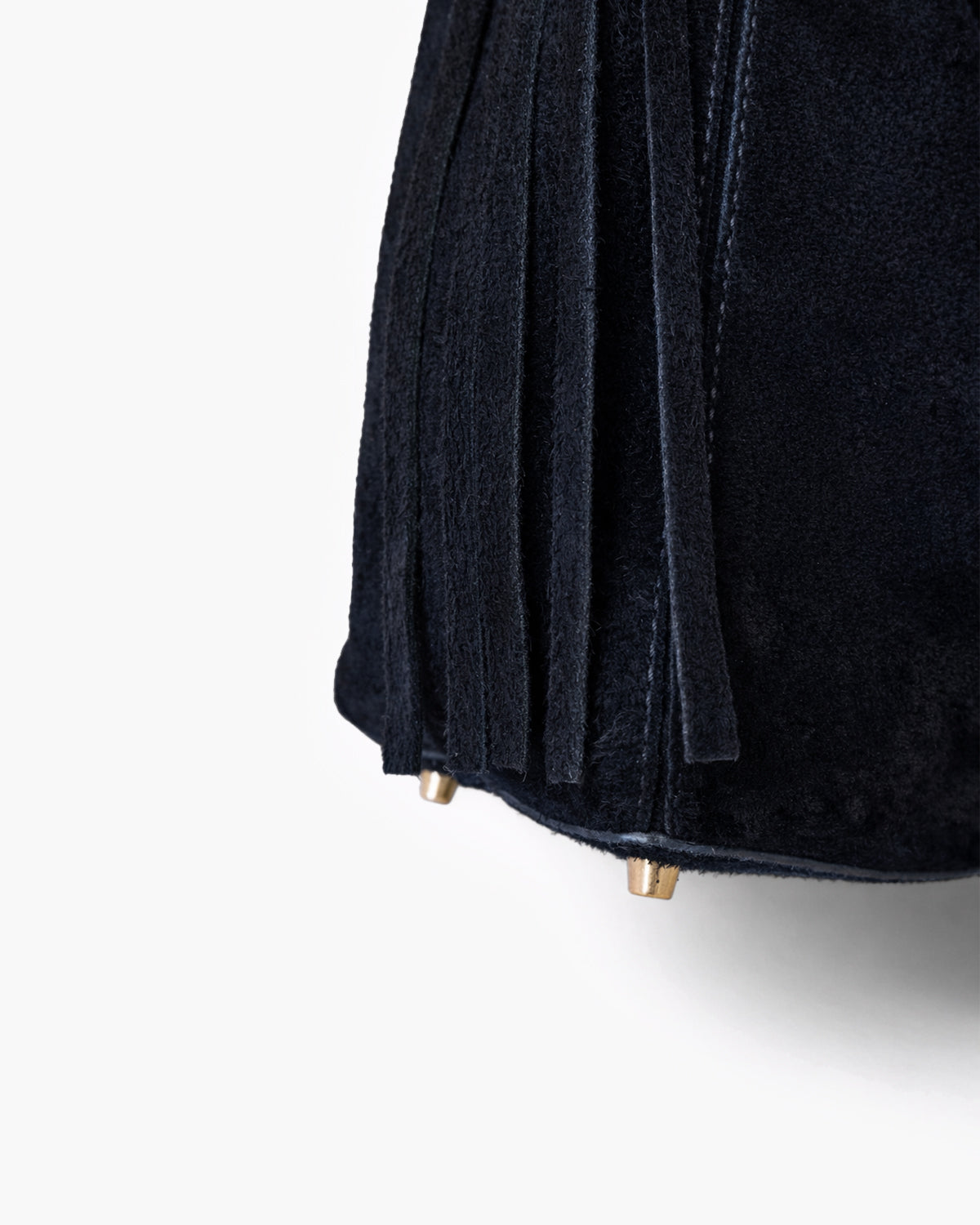 Close-up of a black handbag with fringe details on a white background