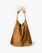 Brown handbag with fur pom-pom handles on a white background