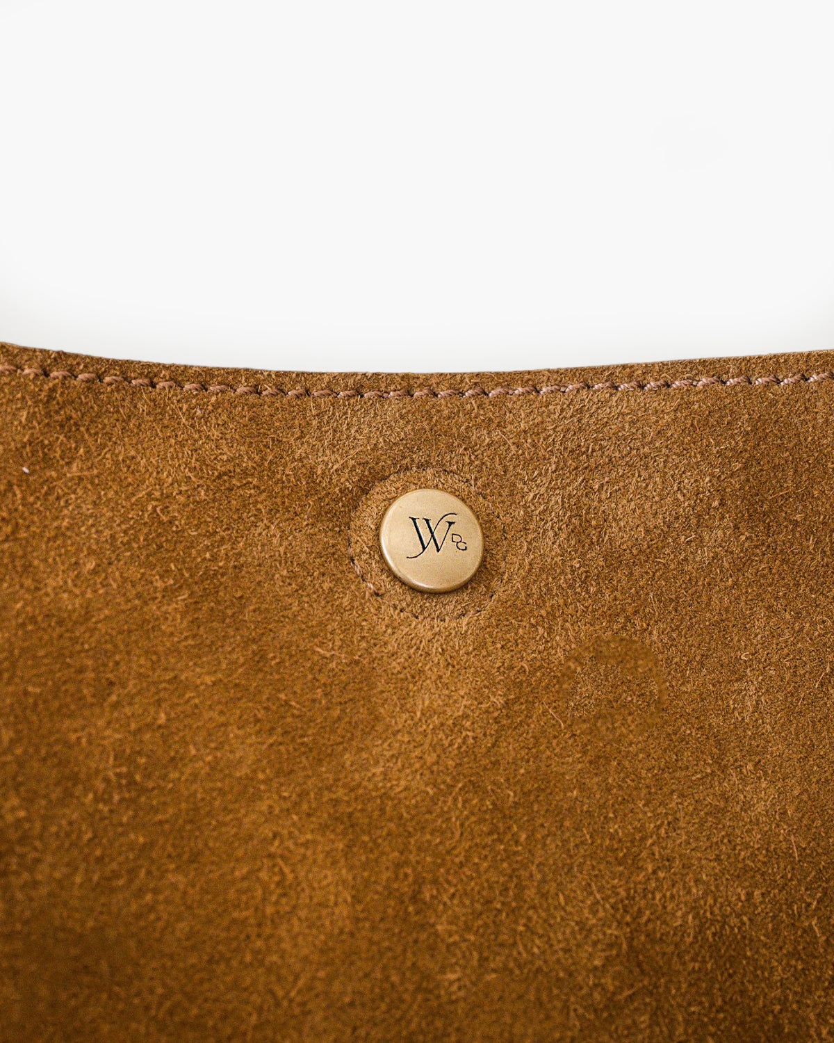 Close-up of a brown leather product with a gold logo on a white background