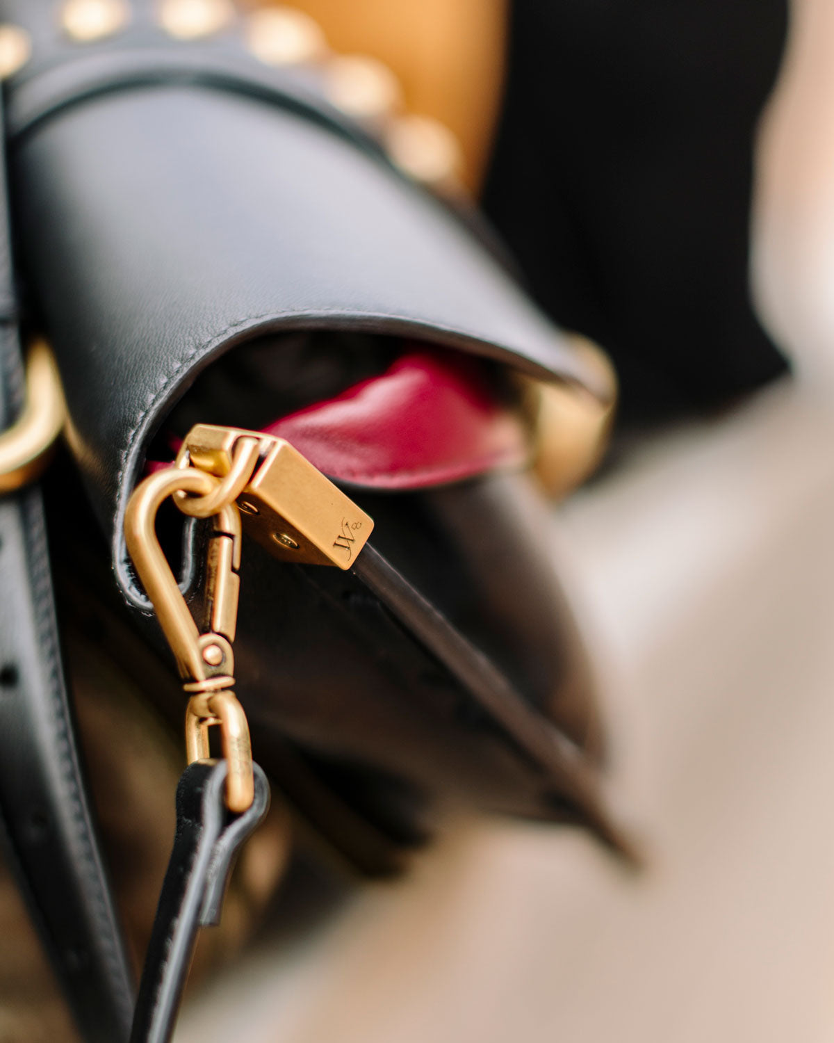 Close-up of a black handbag with gold hardware on a blurred background