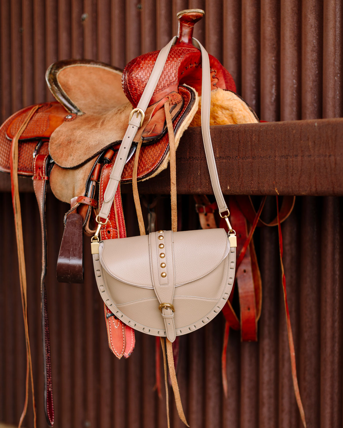 Saddle and leather bag hanging against a brown background