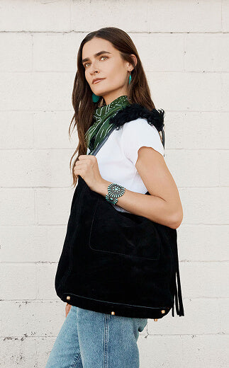 Woman holding a black bag against a white brick wall